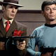 Spock, dressed in a brown suit and fedora, and Dr. McCoy, hold up tommy guns in a scene from "A Piece of the Action."